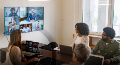 Group meeting with a video call displayed on a screen in a conference room
