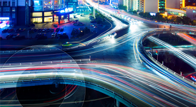 Nighttime city street scene with glowing traffic lights and towering buildings, creating a vibrant urban atmosphere