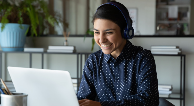 Person wearing headphones using a laptop at a desk