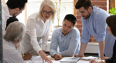  A group of business professionals collaborates around a computer, discussing strategies and sharing ideas.