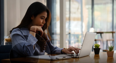 A person seated at a table, focused on a laptop