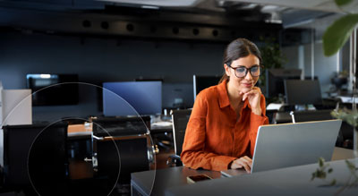 An employee confidently review information on their laptop in an large office space