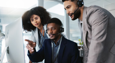 Three people wearing headsets working together at a computer